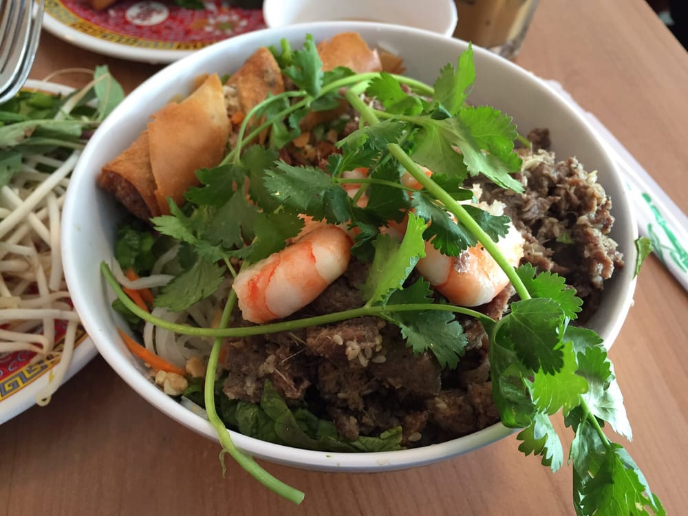 Vermicelli bowl with grilled steak, shrimp, an egg roll and herbs